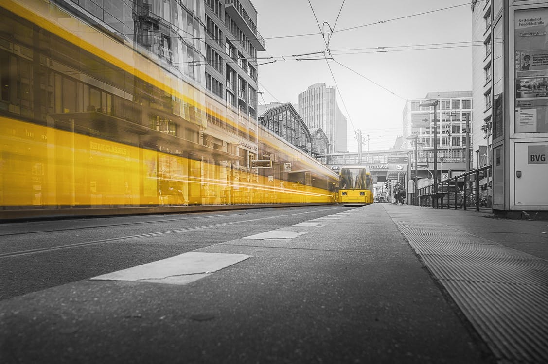 Eine gelbe Bahn fährt durch eine Stadt. Das ist umweltfreundlicher als Autos.
